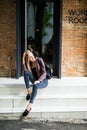 Casual style. Stylish woman in sunglasses sitting on the stone stairs. She dressed in jacket, skinny jeans and shoes. Long hair, e Royalty Free Stock Photo