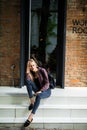 Casual style. Stylish woman in sunglasses sitting on the stone stairs. She dressed in jacket, skinny jeans and shoes. Long hair, e Royalty Free Stock Photo