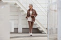 Stylish woman walking city street. Short hair Model wears beige business suit, belt purse, fashion accessories, loafers
