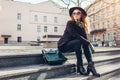 Stylish woman wearing hat, glasses with green handbag and gloves outdoors. Spring clothes, accessories. Female fashion