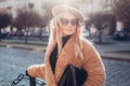 Stylish woman wearing teddy coat beret sunglasses holding purse in city. Spring fashion female accessories and clothes