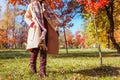 Stylish woman wearing warm clothes shoes and accessories walking in fall park. Autumn female outfit. Burgundy boots Royalty Free Stock Photo