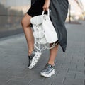 Stylish women`s clothing. Fashionable women`s shoes. Casual design. Close-up of female legs in trendy silver leather sneakers.