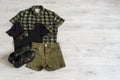 Stylish women`s or teenager`s clothing set with accessories: checkered shirt, black jersey top, green jeans shorts, sunglasses a Royalty Free Stock Photo