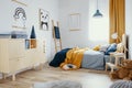 Stylish wooden commode in bright bedroom interior with poster on the wall