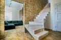 Stylish wooden contemporary staircase inside loft house interior. Modern hallway with decorative limestone brick walls and white Royalty Free Stock Photo