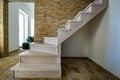 Stylish wooden contemporary staircase inside loft house interior. Modern hallway with decorative limestone brick walls and white Royalty Free Stock Photo