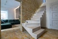 Stylish wooden contemporary staircase inside loft house interior. Modern hallway with decorative limestone brick walls and white Royalty Free Stock Photo
