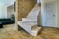 Stylish wooden contemporary staircase inside loft house interior. Modern hallway with decorative limestone brick walls and white Royalty Free Stock Photo