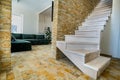 Stylish wooden contemporary staircase inside loft house interior. Modern hallway with decorative limestone brick walls and white Royalty Free Stock Photo