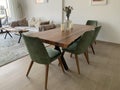 Stylish wooden dining table with green chairs in an open plan living room