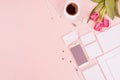 Stylish working space with flowers tulips, coffee cup, phone and blank white stationery on pastel soft pink background, copy space Royalty Free Stock Photo