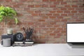 Stylish working space with laptop, coffee cup, pencil holder and potted plant on white table. Blank screen and copy space for