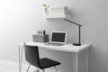 Stylish workplace with laptop and chair near white wall indoors. Interior design Royalty Free Stock Photo