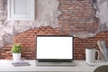 Stylish workplace with laptop computer, coffee cup, stationery and houseplant on white table against brick wall. Blank screen for Royalty Free Stock Photo