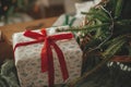 Stylish wrapped christmas gift, rustic basket with fir branches and modern decorations on table close up. Merry Christmas and Royalty Free Stock Photo