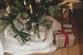 Stylish wrapped christmas gifts and rustic basket with fir branches under festive decorated christmas tree in scandinavian room. Royalty Free Stock Photo