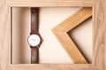 Stylish wristwatch with leather band in wooden frame on beige background Royalty Free Stock Photo