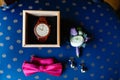 Stylish wristwatch in a wooden box. Pink bow tie, beautiful glass cufflinks, flower boutonniere. A men's set of accessories on an Royalty Free Stock Photo