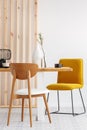 Stylish yellow chair at wooden dining table in trendy interior