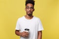 Stylish young afro american man holding cup of take away coffee isolated over yellow background Royalty Free Stock Photo