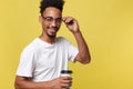 Stylish young afro american man holding cup of take away coffee isolated over yellow background Royalty Free Stock Photo