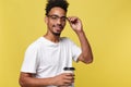 Stylish young afro american man holding cup of take away coffee isolated over yellow background Royalty Free Stock Photo