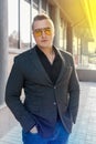 Stylish young attractive guy of European appearance businessman portrait in jacket, shirt and jeans, in sunglasses on the street Royalty Free Stock Photo