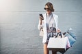 Stylish, young and attractive woman shopping and texting on her phone with copy space. Gorgeous caucasian lady, holding Royalty Free Stock Photo