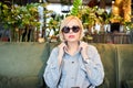 Stylish young blonde in sunglasses sitting at a table in a beautiful restaurant waiting for an order. The woman has a break in the Royalty Free Stock Photo