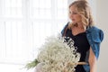 Stylish young blonde woman with a bouquet of gypsophila. Portrait in the interior.