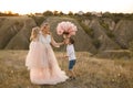 Stylish young boy gives a big flower to his mom in a field at sunset Royalty Free Stock Photo