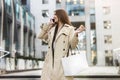 Stylish young businesswoman walks down the stairs in the middle of the street carrying shopping bag, talks on phone , style and