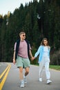 Stylish young couple man and woman walking holding hands on a forest road on a journey and smiling. Vertical Royalty Free Stock Photo