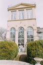 Stylish young couple near the old beige house with columns and big vintage windows. Romantic wedding in Paris Royalty Free Stock Photo