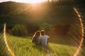 Stylish young couple sitting on a hill and admiring the sunset. A film photo with a light and a sunlight, without a face