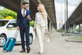 stylish young couple smiling each other while going with suitcase