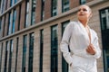 Stylish young European girl in a business suit. Caucasian lady looks to the side on a summer day against the backdrop of buildings