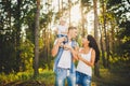 Stylish young Family of mom, dad and daughter one year old blonde sitting near father on shoulders, outdoors outside the city in a Royalty Free Stock Photo