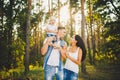 Stylish young Family of mom, dad and daughter one year old blonde sitting near father on shoulders, outdoors outside the city in a Royalty Free Stock Photo