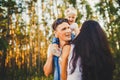 Stylish young Family of mom, dad and daughter one year old blonde sitting near father on shoulders, outdoors outside the city in a Royalty Free Stock Photo