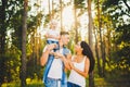 Stylish young Family of mom, dad and daughter one year old blonde sitting near father on shoulders, outdoors outside the city in a Royalty Free Stock Photo