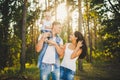 Stylish young Family of mom, dad and daughter one year old blonde sitting near father on shoulders, outdoors outside the city in a Royalty Free Stock Photo