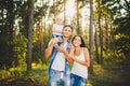 Stylish young Family of mom, dad and daughter one year old blonde sitting near father on shoulders, outdoors outside the city in a Royalty Free Stock Photo