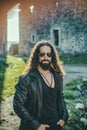 Stylish young fashionable man with long wavy hair wearing bikers leather jacket and sunglasses. Self confident handsome Royalty Free Stock Photo