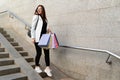 Stylish young girl with multi-colored bags after shopping goes down the stairs Royalty Free Stock Photo