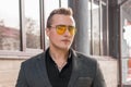 Stylish young guy portrait businessman of European appearance in a gray jacket and black shirt in sunglasses on the street outdoor Royalty Free Stock Photo