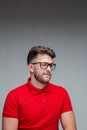 Stylish young guy wink in glasses, studio portrait on gray. Myopia correction by spectacles, ophthalmology. Vision check Royalty Free Stock Photo