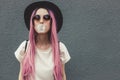 Stylish young hipster woman with long pink hair blowing a bubble with bubble gum. Royalty Free Stock Photo