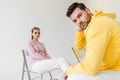 stylish young male and female models in pink and yellow hoodies sitting on chairs Royalty Free Stock Photo